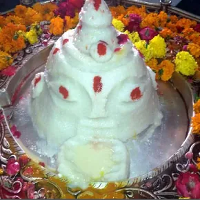 Traditional Indian sweet Shivling made from sugar and decorated with red markings and flowers during religious offering