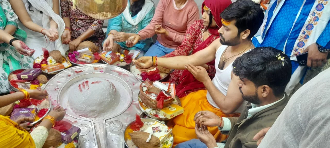 Devotees gathered around a Shiva Lingam during a vibrant Pitra Dosh Puja, offering prayers and placing colorful items and flowers, showcasing Hindu spiritual traditions.